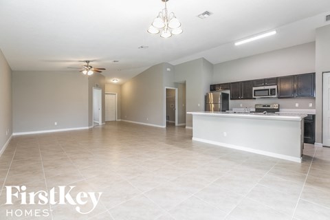 A spacious kitchen and living room with a white ceiling and tiled floor.