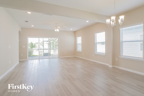 an empty living room with a window and a ceiling fan