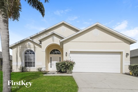 a beige house with a garage door and a lawn
