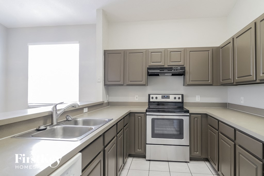 a kitchen with brown cabinets and a sink and a stove