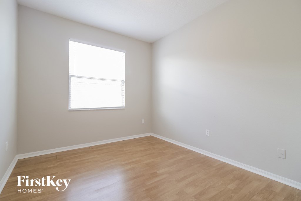 an empty room with a window and wooden floors