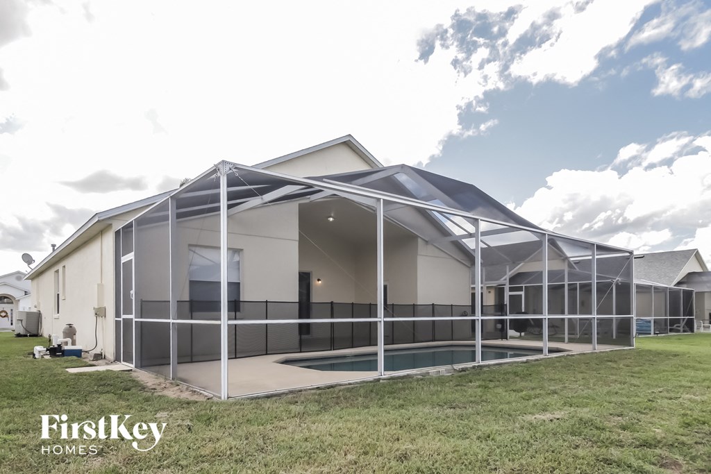 a glass enclosure around a swimming pool in front of a house