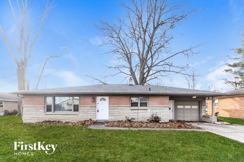 a small brick house with a white door and a tree