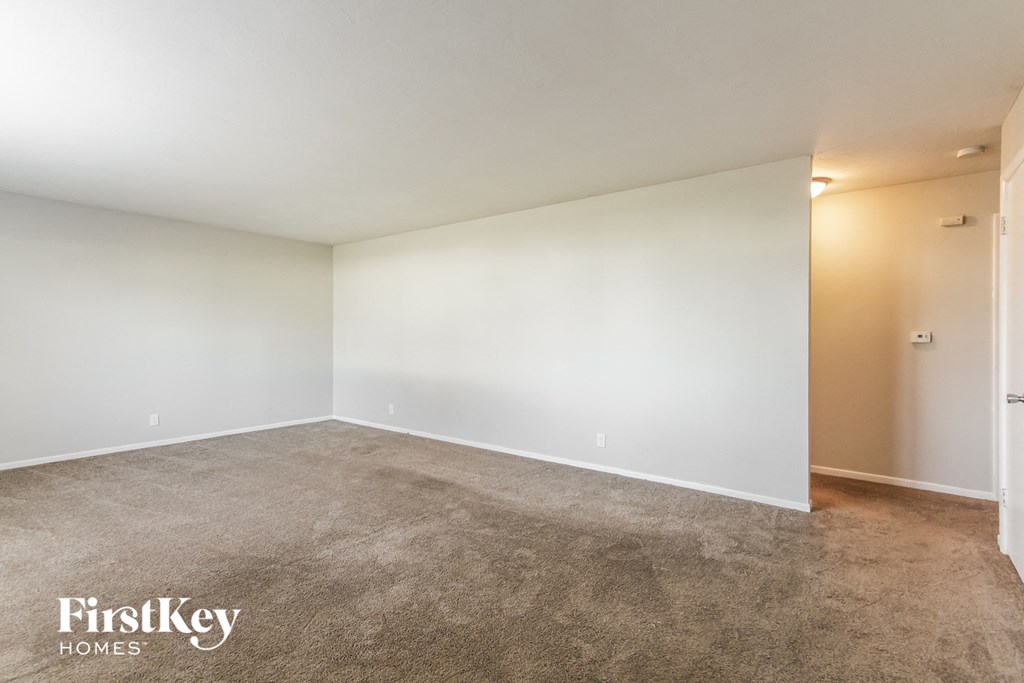 an empty living room with white walls and carpet
