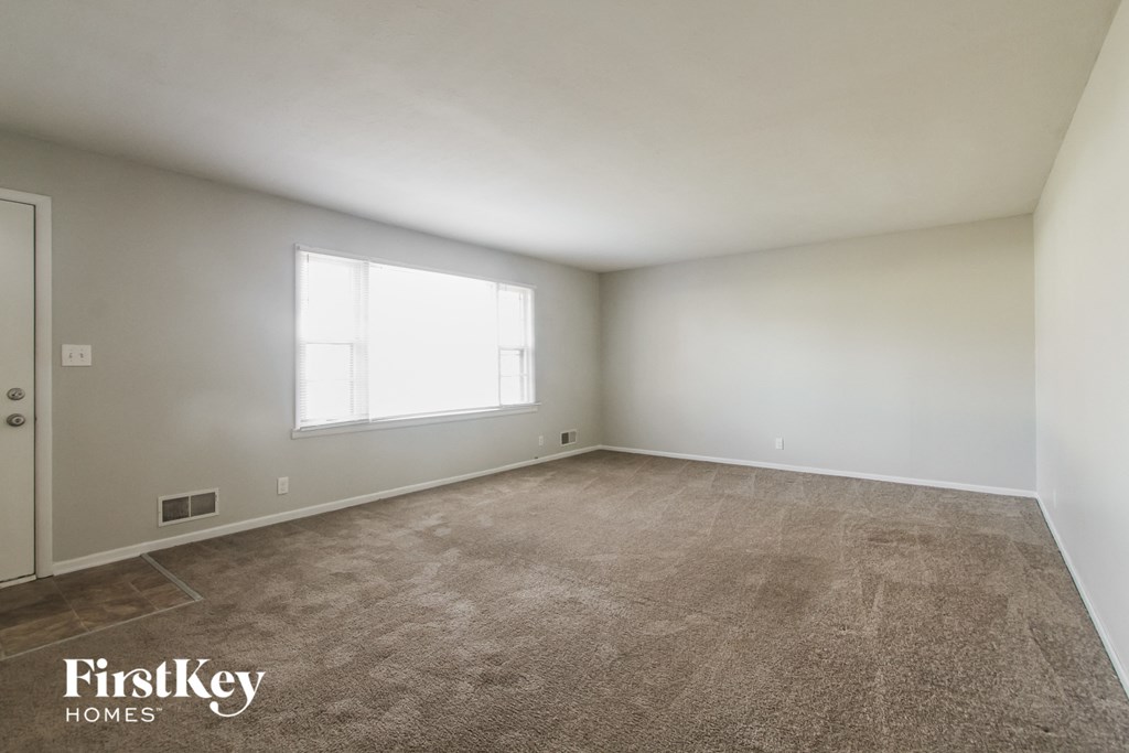 an empty living room with carpet and a window