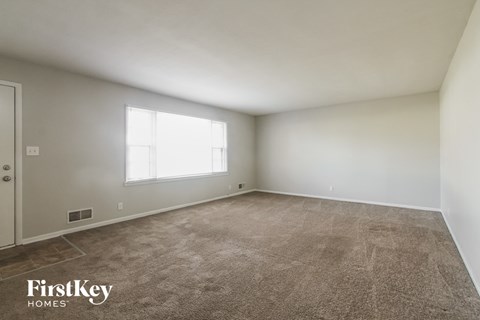 an empty living room with carpet and a window