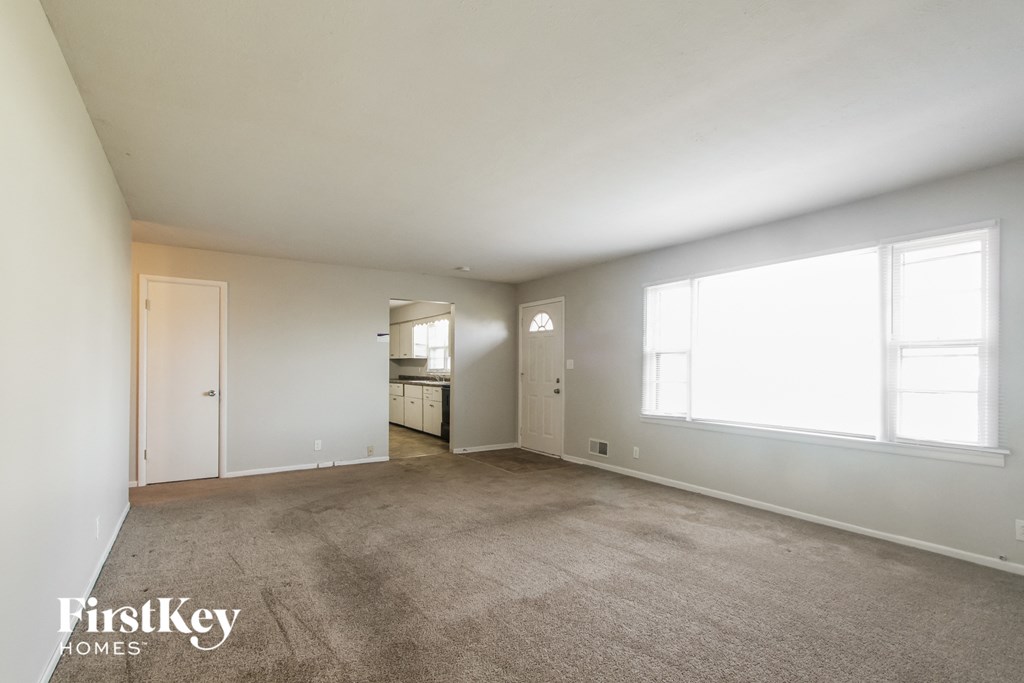 an empty living room with carpet and a large window
