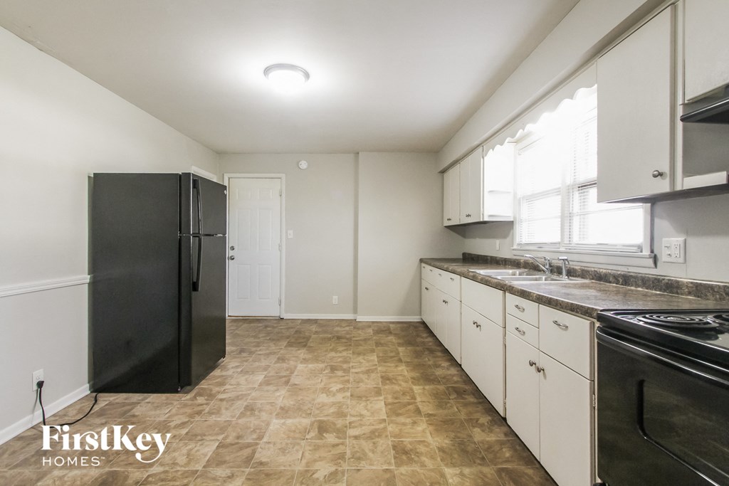a kitchen with white cabinets and black appliances and a black refrigerator