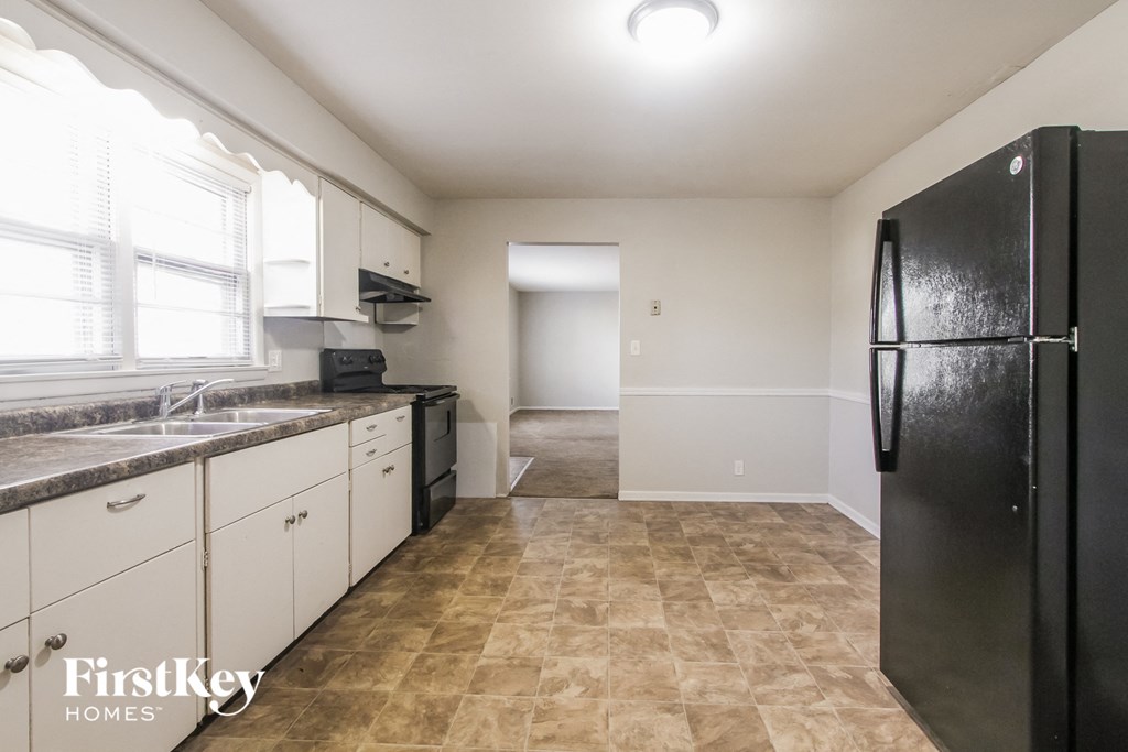 a kitchen with white cabinets and a black refrigerator