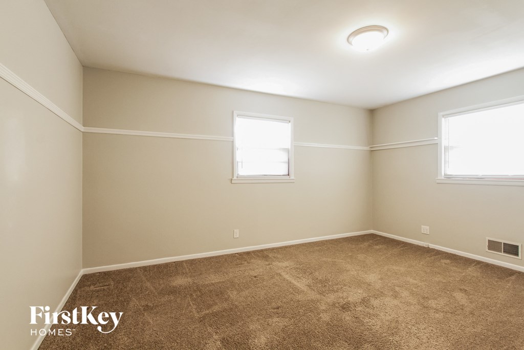 a empty room with carpet and two windows
