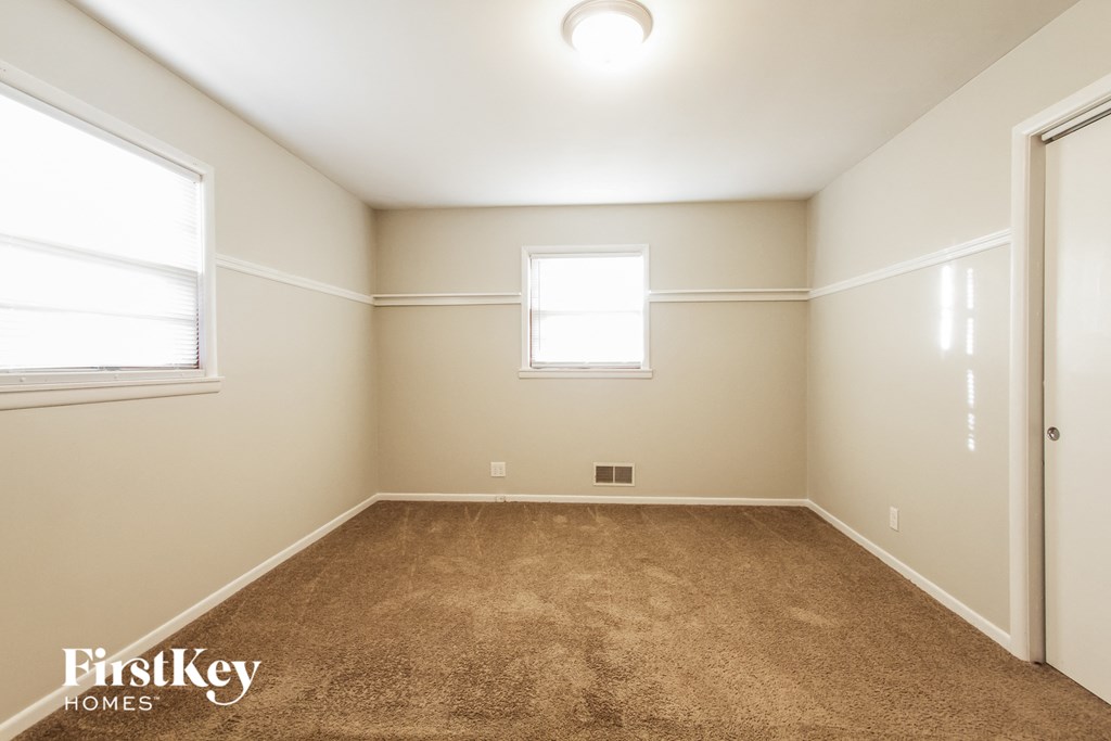 a empty room with carpet and two windows