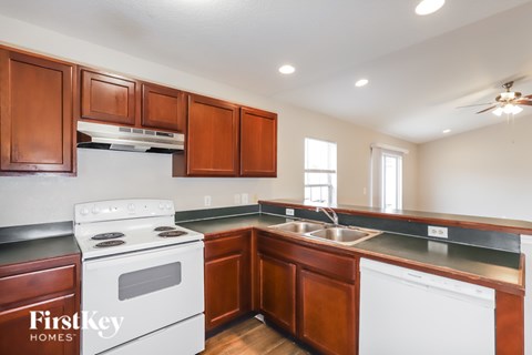 A kitchen with wooden cabinets and a white stove top oven.
