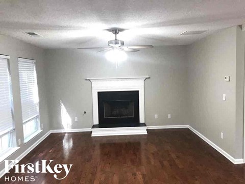 an empty living room with a fireplace and a ceiling fan