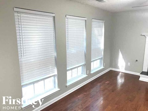 a living room with three windows and a hard wood floor