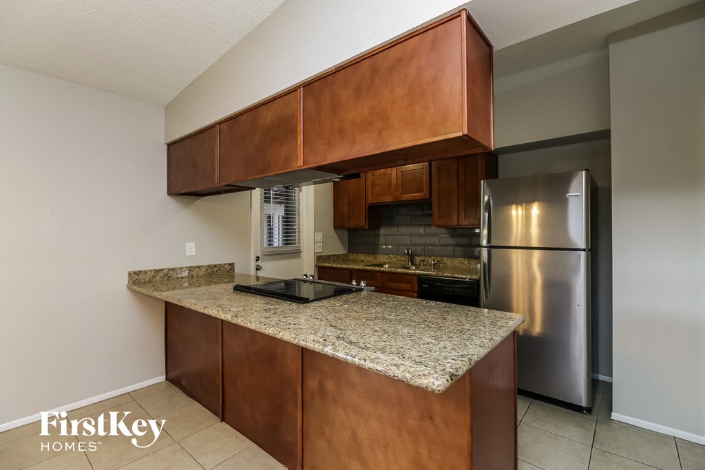 a kitchen with a granite counter top and stainless steel refrigerator
