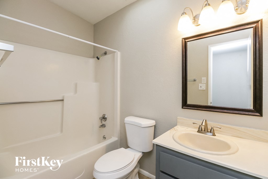 a bathroom with a toilet sink and mirror and a shower