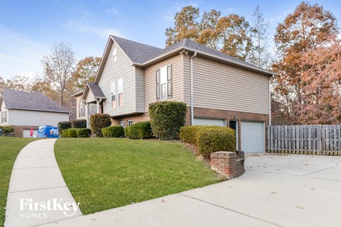 a gray house with a yard and a white fence