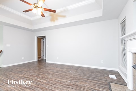 a empty living room with white walls and a ceiling fan