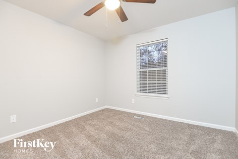 the spacious living room with ceiling fan and carpet