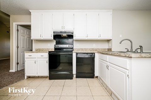 A kitchen with white cabinets and a black oven.
