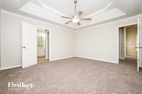 A spacious room with a ceiling fan and carpeted floor.