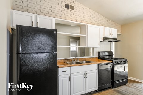 a kitchen with white cabinets and a black refrigerator