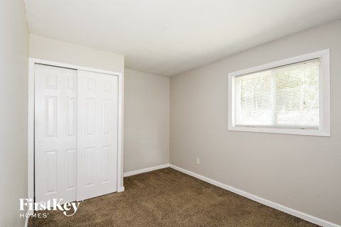 a bedroom with carpet and a white door and a window