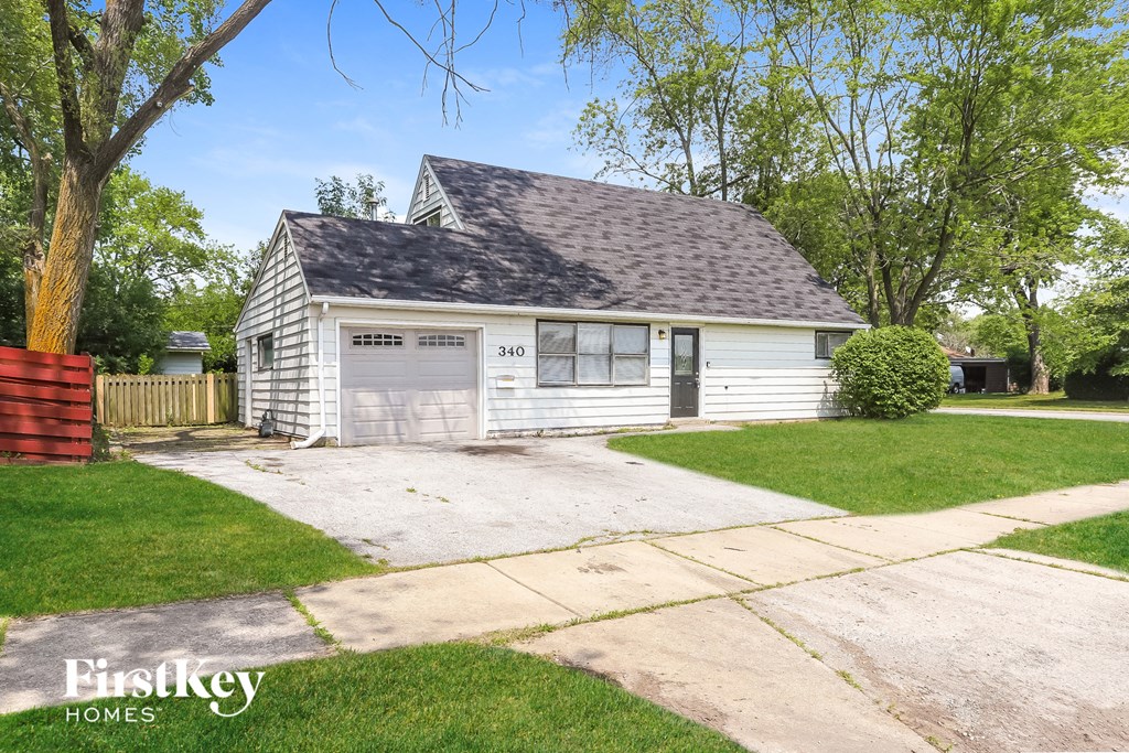 a small white house with a garage and a driveway