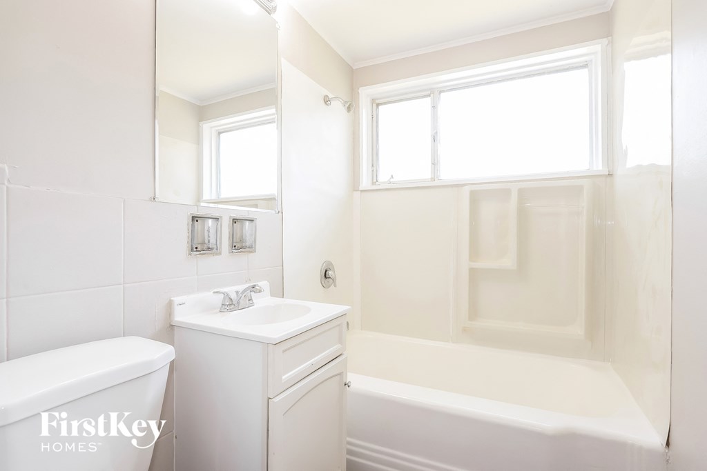 a white bathroom with a tub and a sink and a mirror