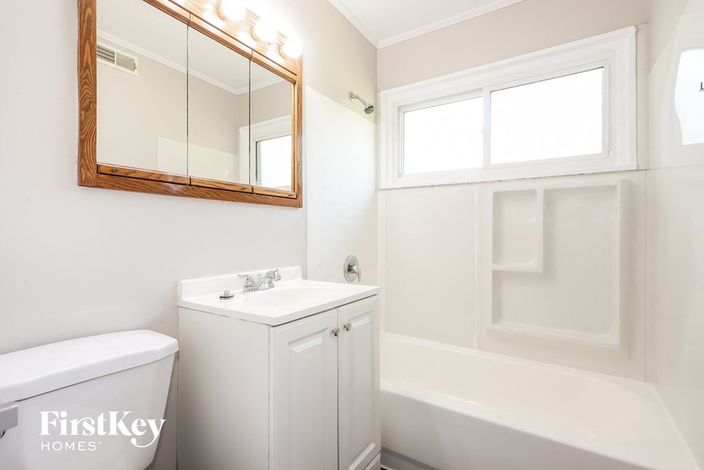 a white bathroom with a white toilet and sink and a white tub