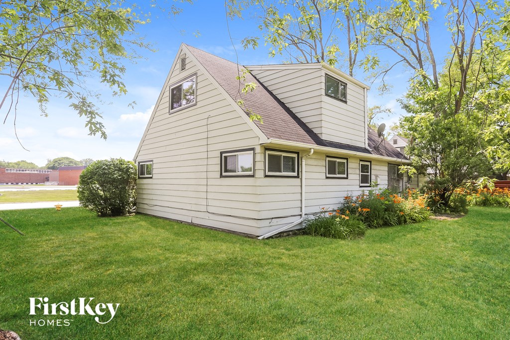 a white house with a peaked roof and a lawn