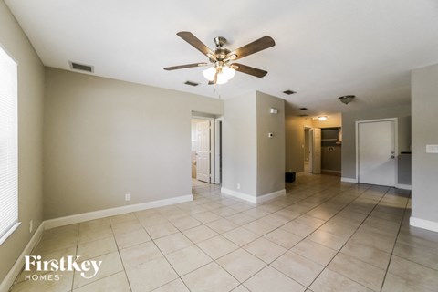 a large living room with tile flooring and a ceiling fan