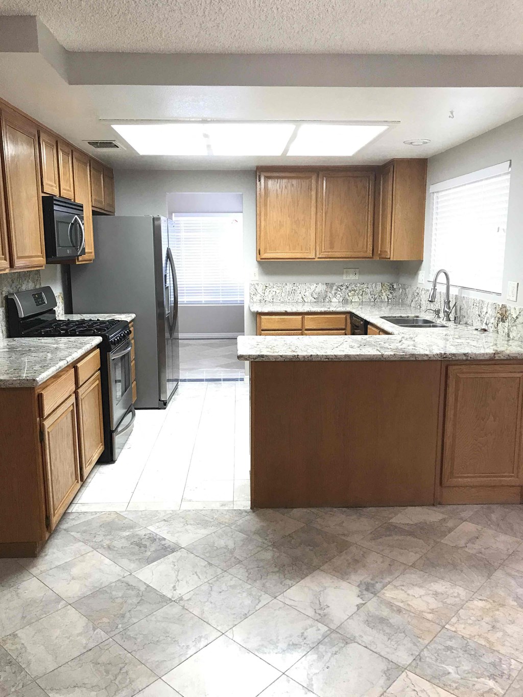 an empty kitchen with wooden cabinets and stainless steel appliances