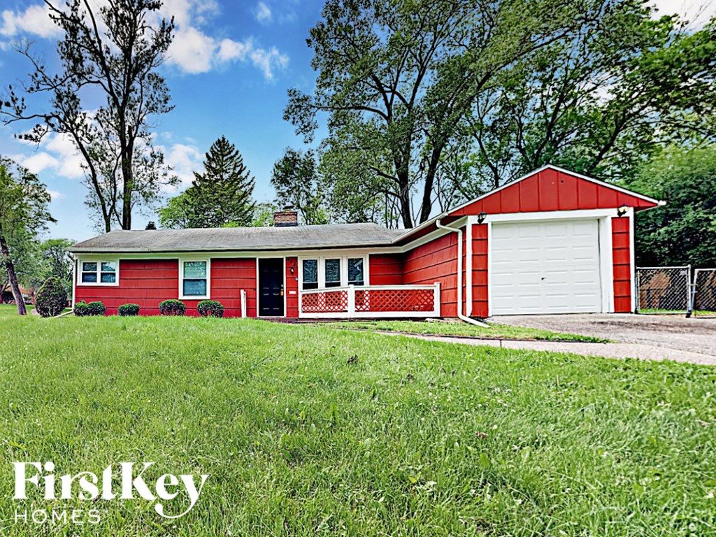 a red house with a red garage and a white fence