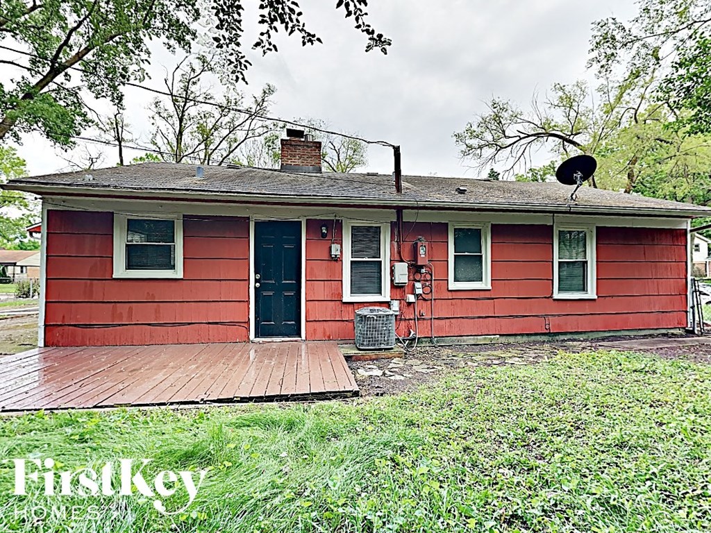 a red house with a porch and a black cat on the roof