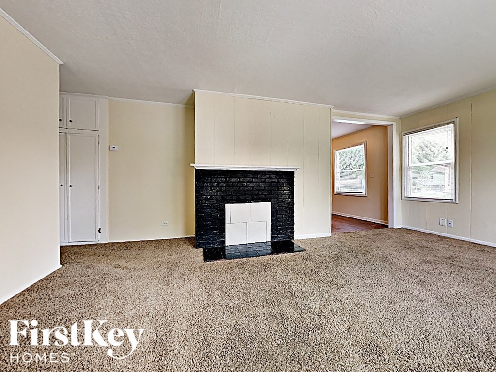 an empty living room with a black fireplace