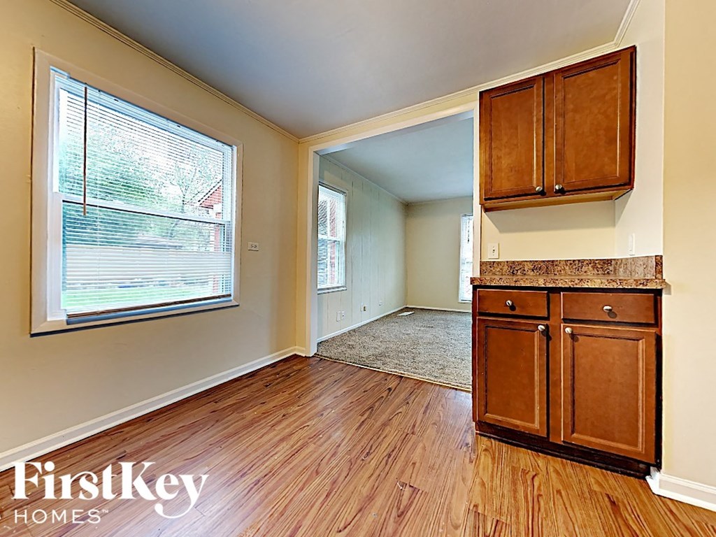an empty kitchen with a large window and wooden floors