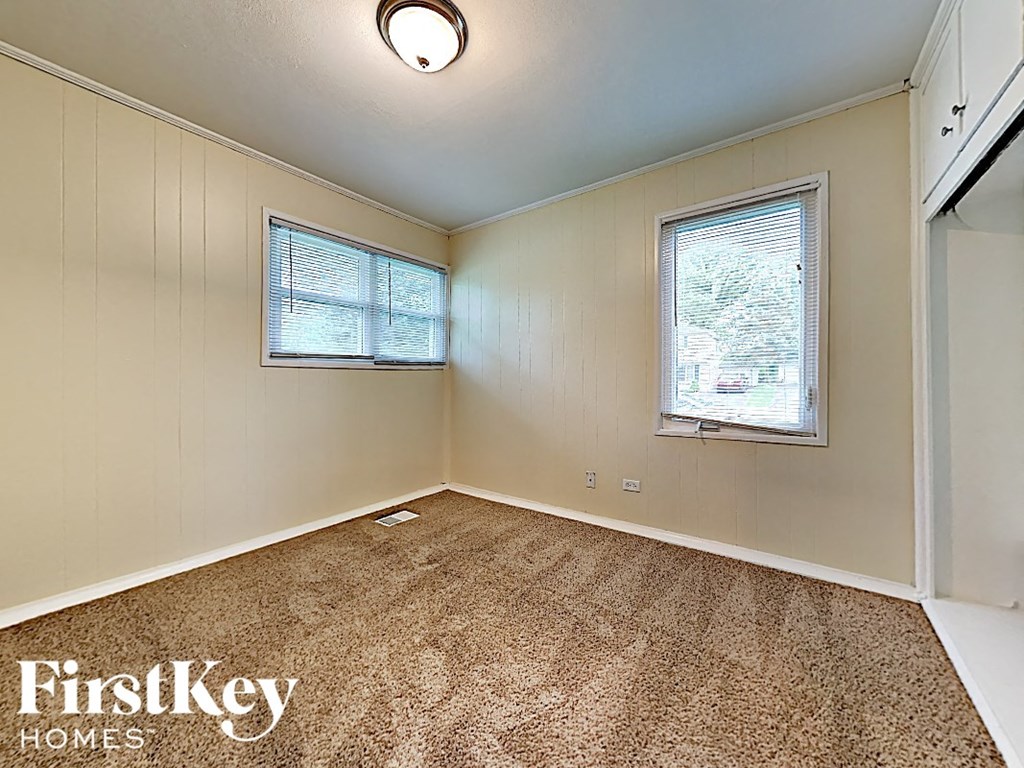 an empty living room with carpet and two windows