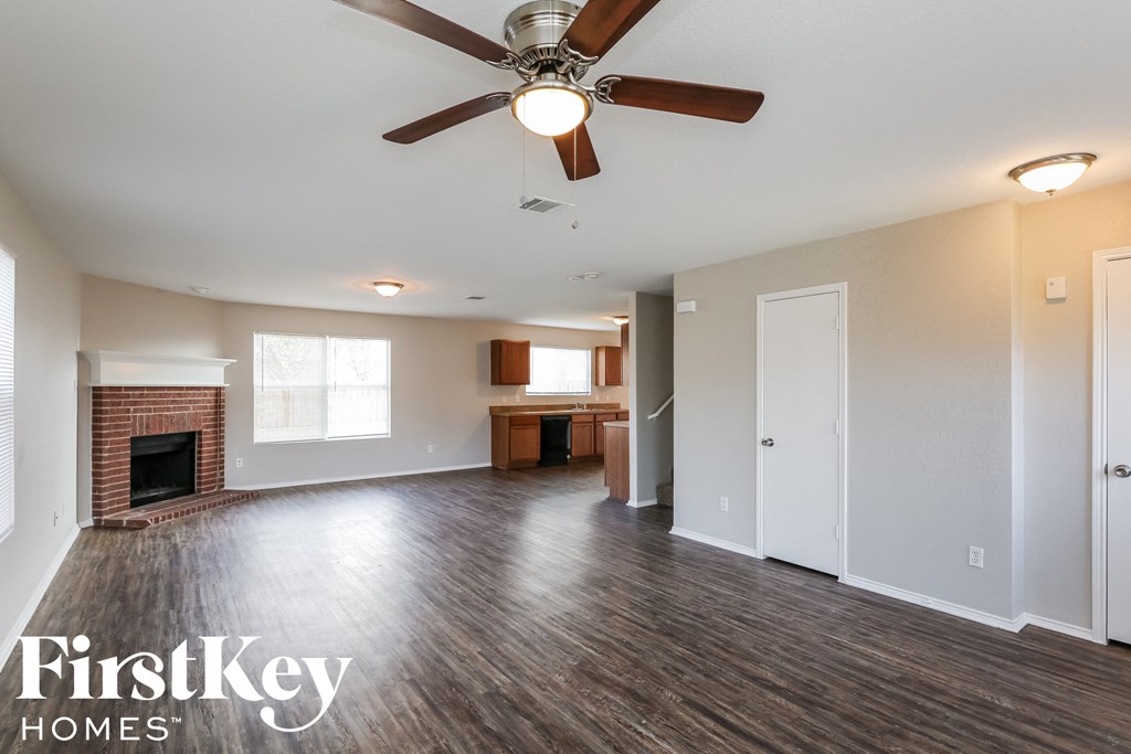 an empty living room with a ceiling fan and a fireplace