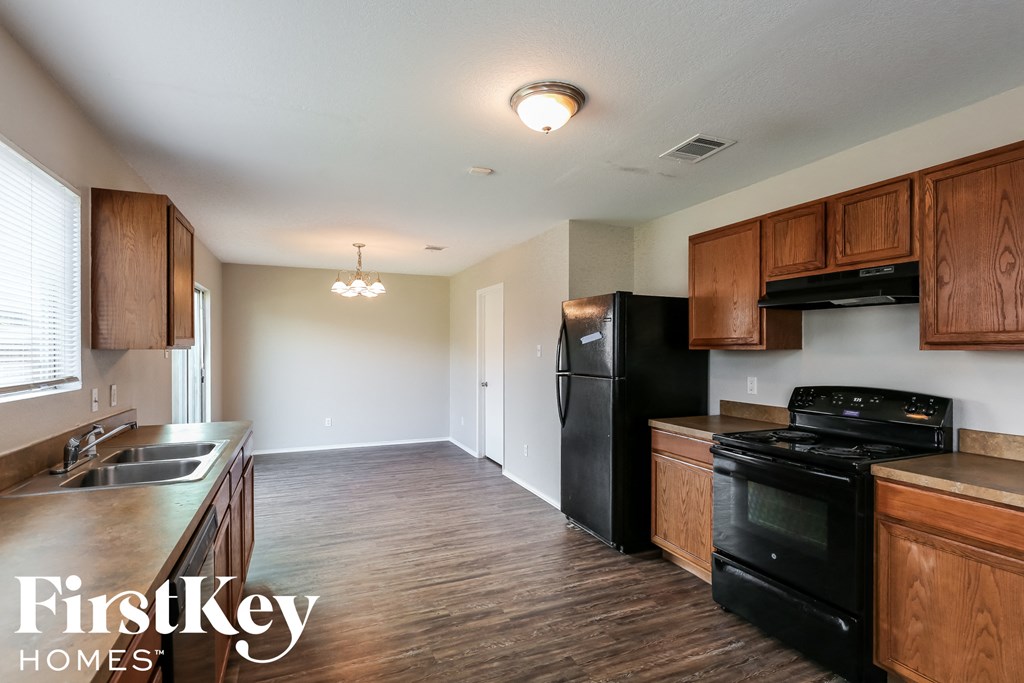 an empty kitchen with black appliances and wooden cabinets