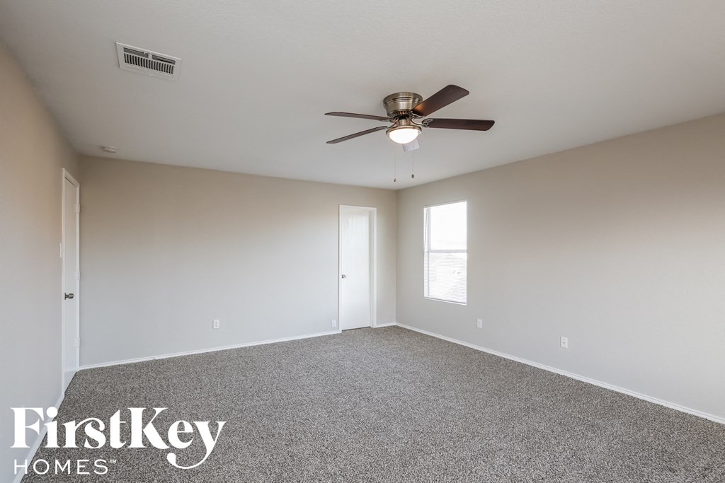 an empty living room with a ceiling fan and a window