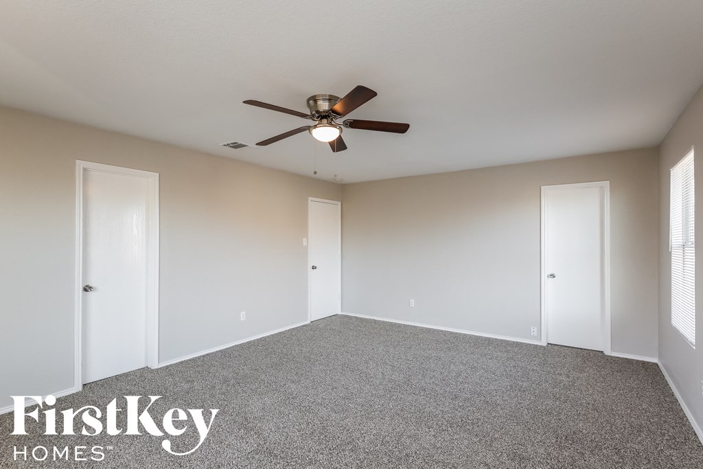 an empty living room with a ceiling fan and white doors