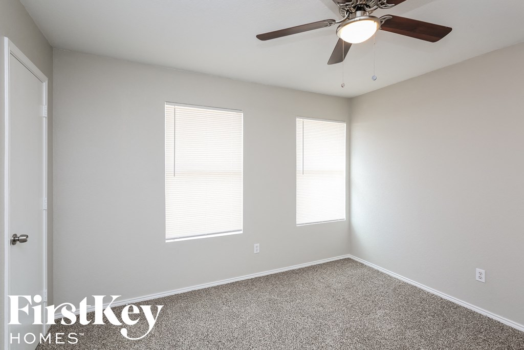a bedroom with a ceiling fan and two windows