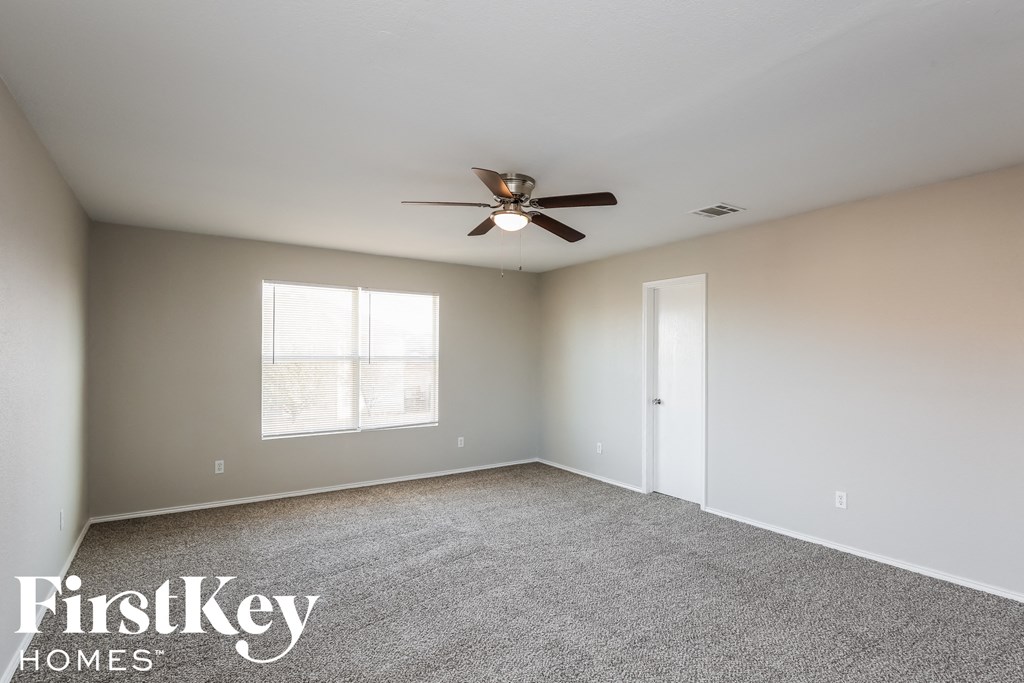 an empty room with a ceiling fan and a window