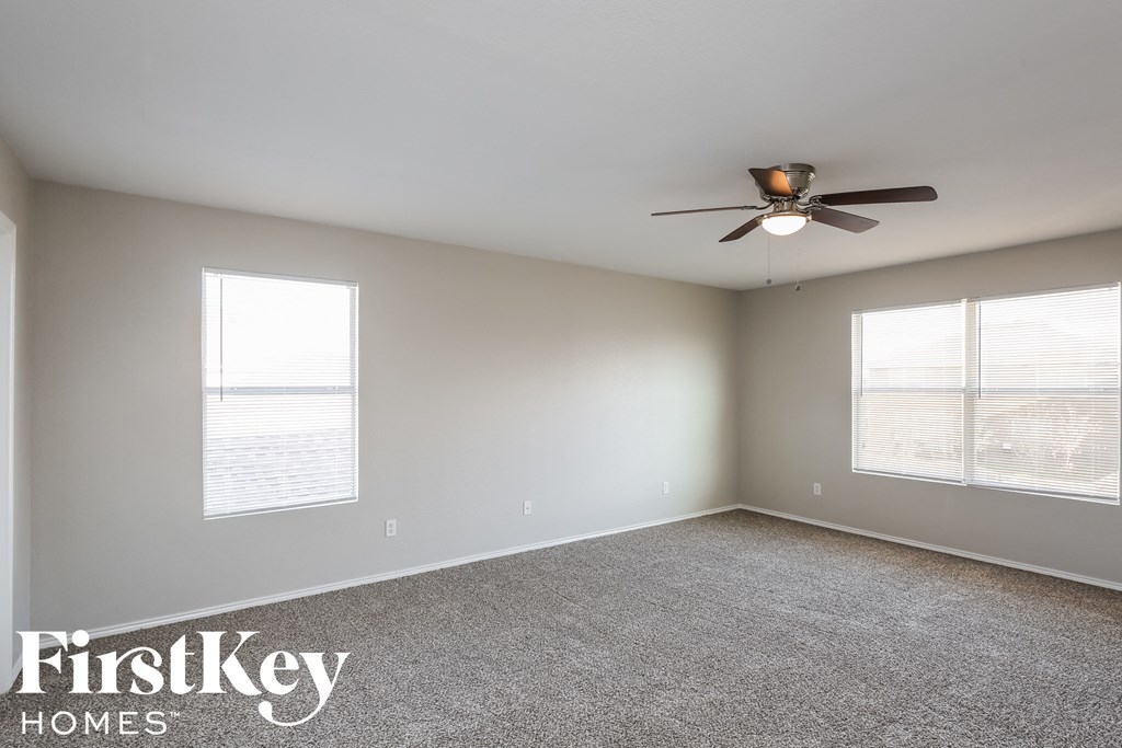 a living room with a ceiling fan and two windows