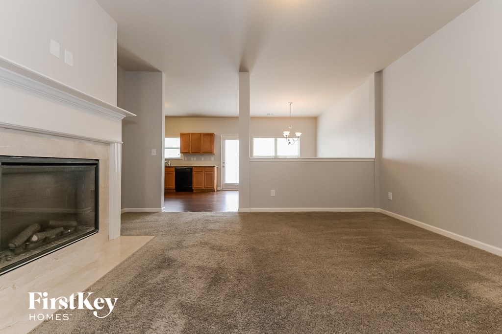 A spacious living room with a fireplace and a carpeted floor.