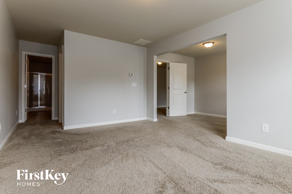 A carpeted room with a doorway leading to another room.