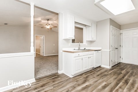 A kitchen with white cabinets and a wooden floor.