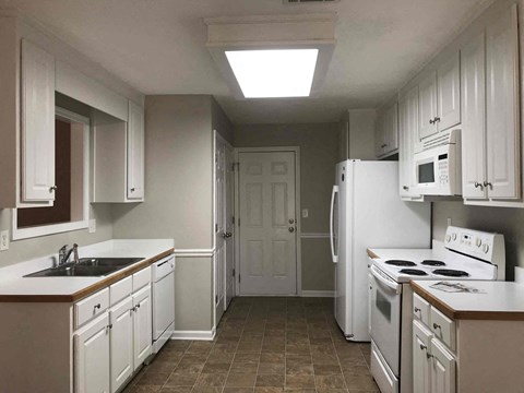 A kitchen with white cabinets and appliances.
