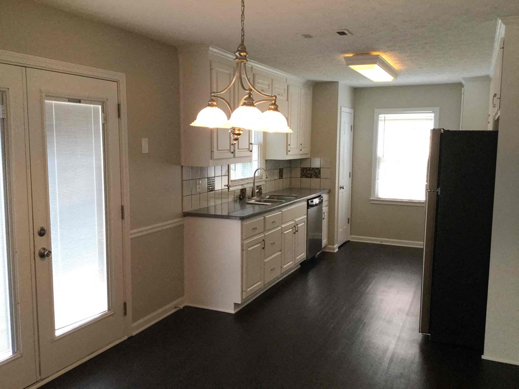 A kitchen with white cabinets and black countertops.